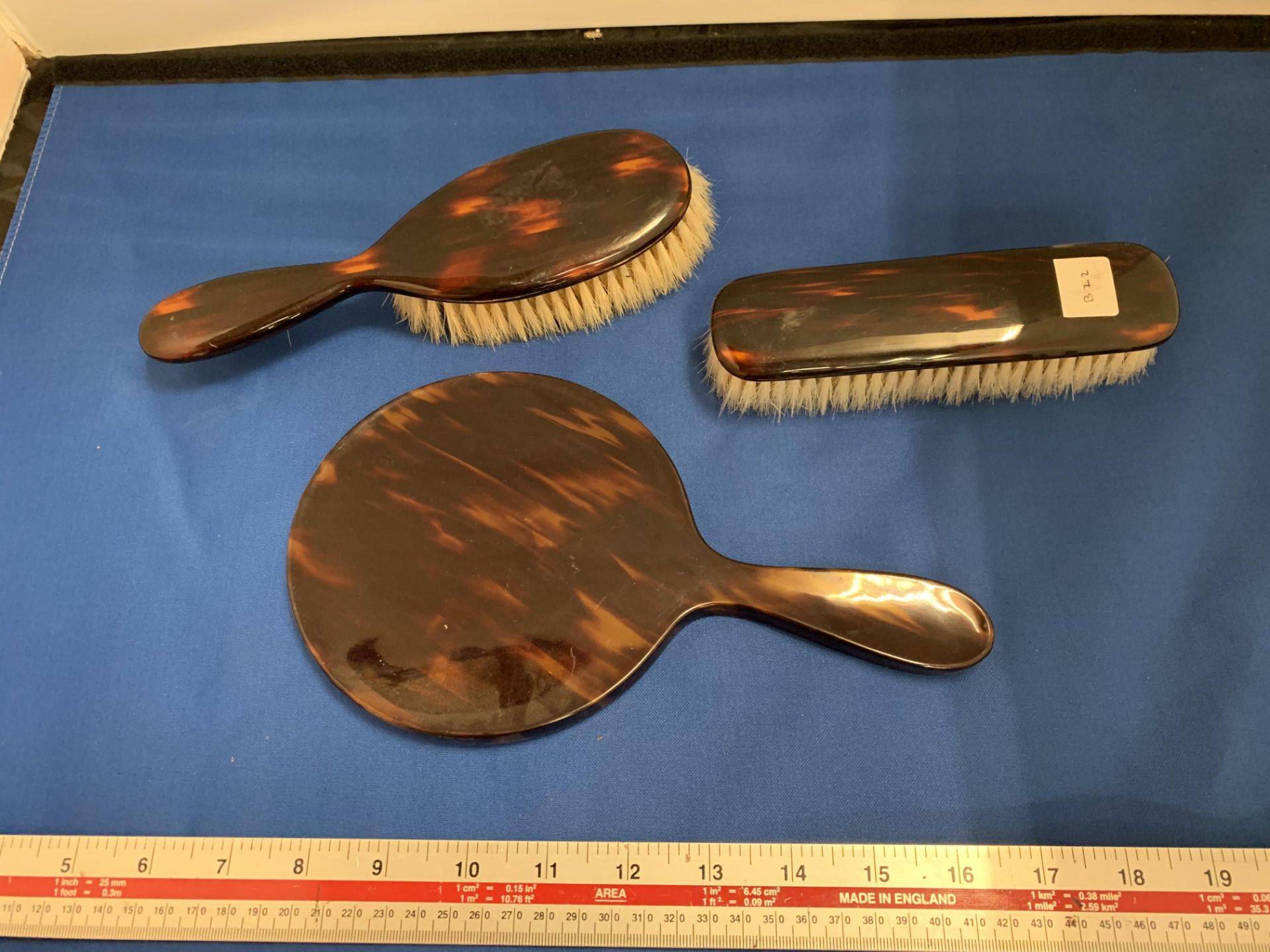 A TORTOISHELL EFFECT THREE PIECE DRESSING TABLE SET COMPRSING OF A MIRROR AND TWO BRUSHES