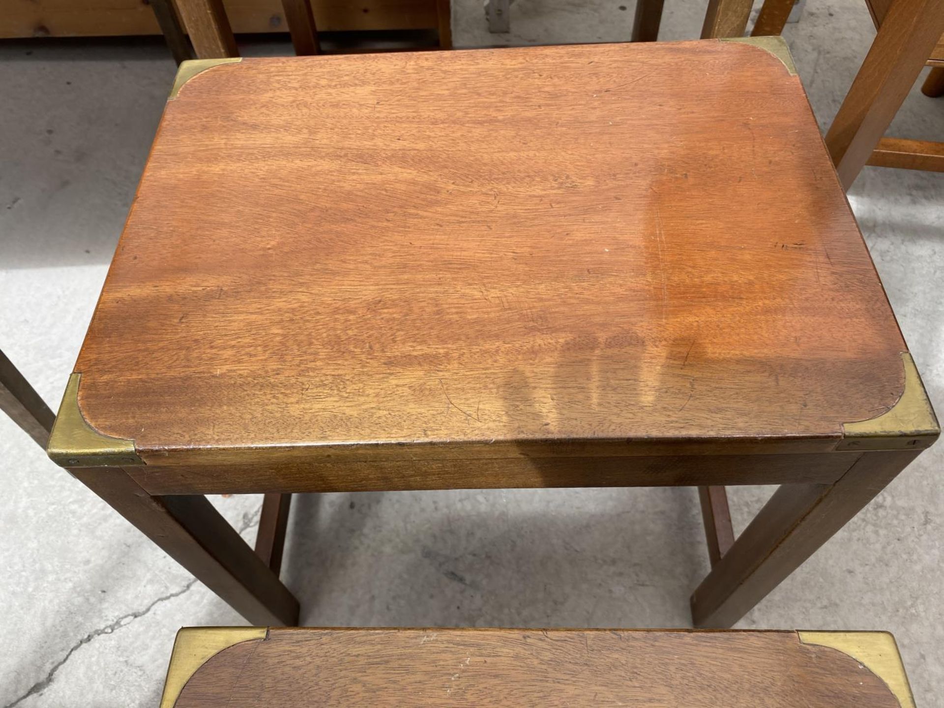 A MAHOGANY NEST OF TABLES WITH BRASS CORNERS AND DECORATION - Image 3 of 4