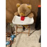 A WOODEN HIGH CHAIR WITH A TEDDY