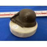 A VINTAGE PAPERWEIGHT WITH GERMAN HELMET, LUGER AND GRENADE