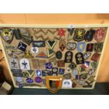 A BOARD WITH NUMEROUS MILITARY CLOTH BADGES AND A MILITARY PLAQUE