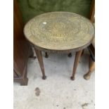 A SMALL INDIAN BRASS TABLE ON MAHOGANY SUPPORTS