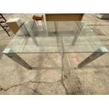 A GLASS DINING TABLE ON CHROME SUPPORTS