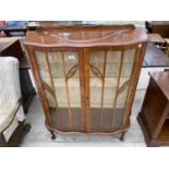 A MAHOGANY SERPENTINE FRONT CHINA CABINET ON CABRIOLE SUPPORTS WITH TWO GLAZED PANEL DOORS AND