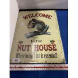 A 'WELCOME TO THE NUT HOUSE' METAL SIGN