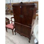 A MAHOGANY COCKTAIL CABINET ON CABRIOLE SUPPORTS WITH FOUR DOORS, CARVED DECORATION AND ELABORATE