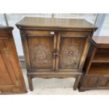 AN OAK COCKTAIL CABINET WITH TWO CARVED PANEL DOORS AND INNER FITTINGS