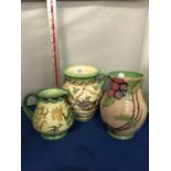 THREE CHARLOTTE RHEAD CROWN DUCAL JUGS AND VASE, GREEN, CREAM AND YELLOW TONES