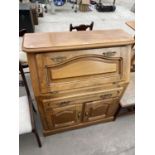 AN OAK BUREAU WITH FALL FRONT, TWO DOORS AND ONE DRAWER