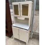 A VINTAGE KITCHEN CABINET WITH TWO LOWER DOORS, TWO UPPER GLAZED DOORS AND ENAMEL TOP
