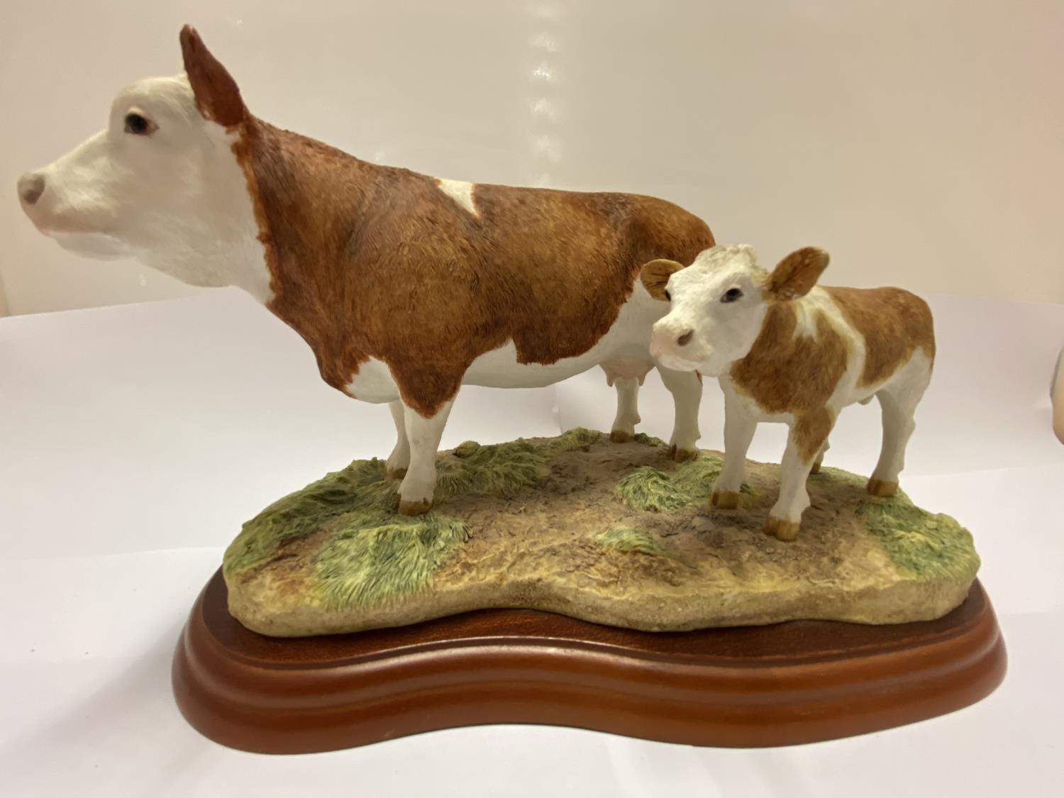 A BORDER FINE ARTS SIMMENTAL COW AND CALF ON WOODEN PLINTH