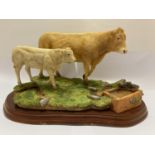 A BORDER FINE ARTS BLONDE D'AQUITAINE COW AND CALF ON WOODEN PLINTH