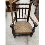 AN INFANTS MINIATURE OAK ARMCHAIR WITH RUSH SEAT