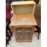 A SMALL PINE CABINET WITH SINGLE GLAZED DOOR AND A PINE EFFECT BOOKCASE