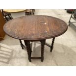 AN OVAL OAK DROP LEAF SIDE TABLE ON BARLEY TWIST SUPPORTS WITH CARVED TOP