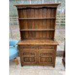 AN OAK WELSH DRESSER WITH TWO DOORS, TWO DRAWERS AND UPPER PLATE RACK