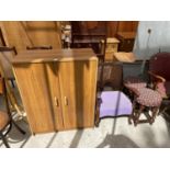 AN OAK EFFECT CABINET, ARMCHAIR AND TWO STOOLS