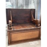 AN OAK MONK'S BENCH WITH CARVED ARMRESTS AND UNDER SEAT COMPARTMENT - CONVERTS TO A TABLE