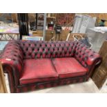 AN OX BLOOD LEATHER BUTTON BACK TWO SEATER SOFA