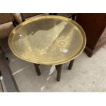 A BRASS TOPPED TABLE ON FOLDING SUPPORT