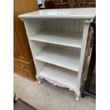 A WHITE THREE TIER BOOKCASE ON CABRIOLE SUPPORTS