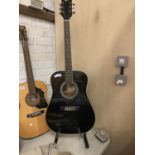 A BLACK HONDO II ACOUSTIC GUITAR ON A STAND