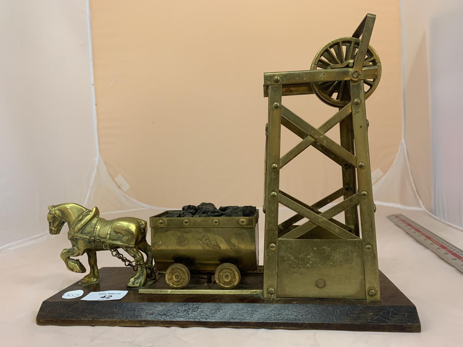 A BRASS MODEL OF A HORSE PULLING COAL FROM MINE ON A WOODEN BASE