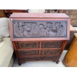 A HEAVILY CARVED ORIENTAL STYLE MAHOGANY BUREAU WITH FALL FRONT, FOUR SHORT AND ONE LONG DRAWER