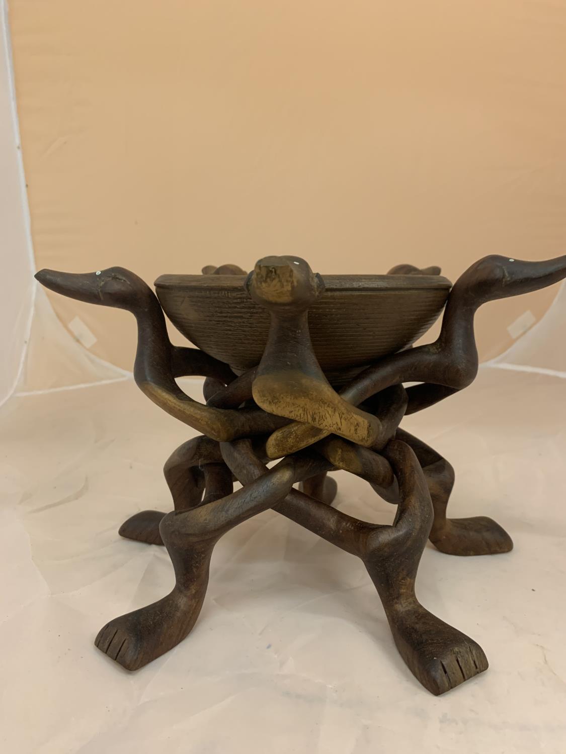 A WOODEN CARVED BOWL ON A STAND AND A FURTHER BOWL