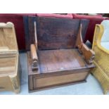 AN OAK MONK'S BENCH WITH LOWER COMPARTMENT AND LION SHAPED ARMRESTS - CONVERTS TO A TABLE