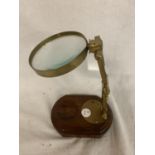 A BRASS MAGNIFYING GLASS ON A MAHOGANY STAND