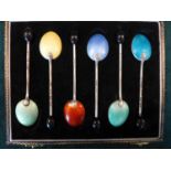 A CASED SET OF SIX SILVER COFFEE BEAN SPOONS, THE BACKS WITH MULTI COLOURED ENAMEL DECORATION