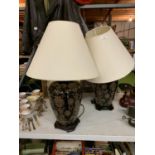 A PAIR OF LARGE ORNATE BLACK AND GILT PATTERNED TABLE LAMPS WITH CREAM SHADES