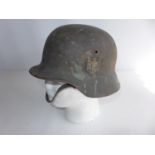 A GERMAN WORLD WAR II HELMET, COMPLETE WIH INNER LINER AND CHIN STRAP. ACCORDING TO THE VENDOR