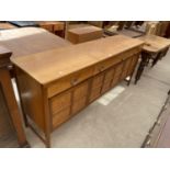 A VINTAGE NATHAN STYLE SIDEBOARD ENCLOSING THREE FRIEZE DRAWERS, TWO END CUPBOARDS AND CENTRAL