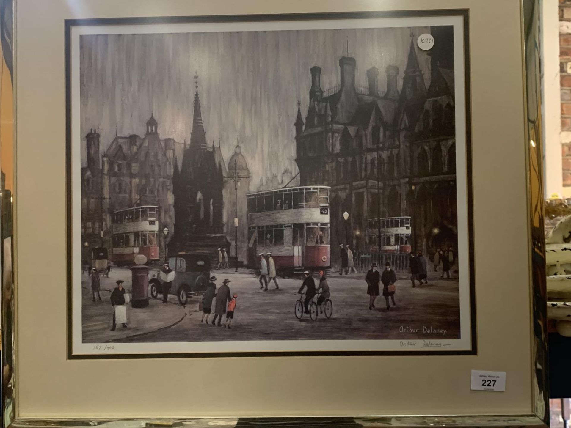 A FRAMED PRINT OF THREE TRAMS IN ALBERT SQUARE, MANCHESTER BY BRITISH ARTIST ARTHUR DELANEY