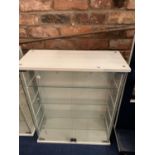 A MODERN WHITE DISPLAY CABINET WITH GLASS SHELVING AND DOORS