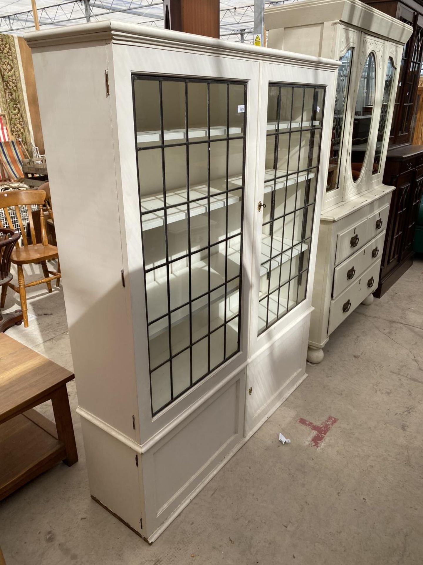 A WHITE PAINTED GLAZED AND LEADED TWO DOOR CABINET WITH CUPBOARD TO BASE