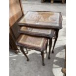 A MAHOGANY NEST OF TABLES WITH LEATHER AND GLASS TOPS