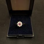 A 9CT GOLD RING SET WITH CENTRE PINK STONE AND EIGHT SURROUNDING CLEAR STONES 1.3 GRAMS
