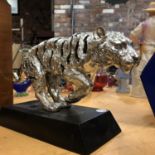 A SILVER COLOURED TIGER STATUE MOUNTED ON A RESIN PLINTH