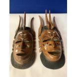 A PAIR OF HEAVILY CARVED INLAID TRIBAL MASKS