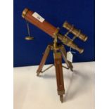 A BRASS AND LEATHER TELESCOPE ON A WOODEN STAND
