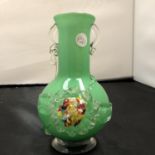 A GREEN GLASS VASE WITH ORNATE FLOWER DESIGN