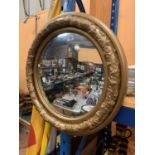 A LARGE ROUND MIRROR FRAMED IN GILT PLASTER WITH VINE RELIEF PATTERN