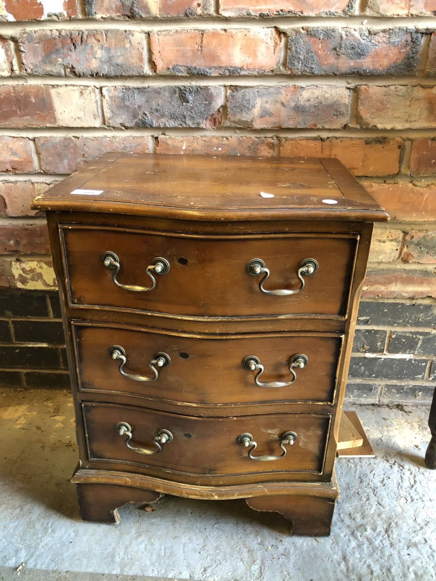 A SMALL WOODEN CHEST OF DRAWERS WITH DROP METAL HANDLES