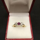 A 18CT YELLOW GOLD RING SET WITH A CENTRE RUBY AND TWO IN LINE DIAMONDS 4.2 GRAMS