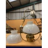 A DECORATIVE BRASS OIL LAMP WITH AN OPAQUE GLASS SHADE AND HANGING HANDLE. TO INCLUDE A SPARE SHADE