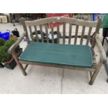 A WOODEN GARDEN BENCH WITH SEAT PAD