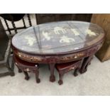 A CARVED AND DECORATED ORIENTAL STYLE COFFEE TABLE HOUSING A NEST OF SIX MATCHING TABLES